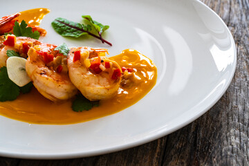 Shrimps salad with ginger and chili in mango sauce on wooden table
