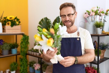 Middle age man florist holding bouquet of flowers at flower shop