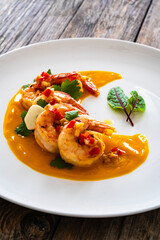 Shrimps salad with ginger and chili in mango sauce on wooden table
