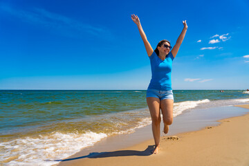Beautiful mid adult woman walking on sunny beach
