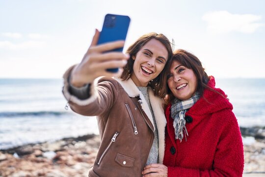 Two women mother and daughter make selfie by smartphone at seaside