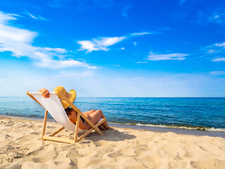 Woman relaxing on beach sitting on sunbed
