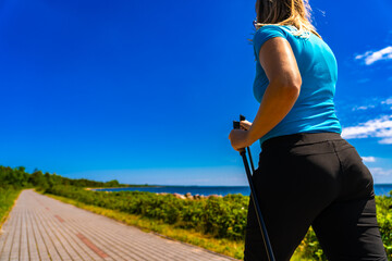 Nordic walking - beautiful woman exercising by the sea
