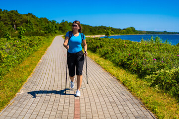 Nordic walking - beautiful woman exercising by the sea
