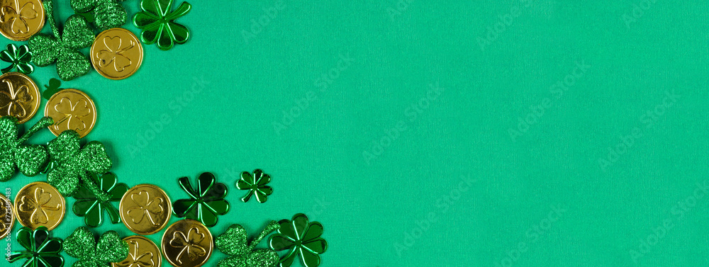 Poster St Patricks Day corner border of  shiny shamrocks and gold coins. Top view over a green banner background with copy space.