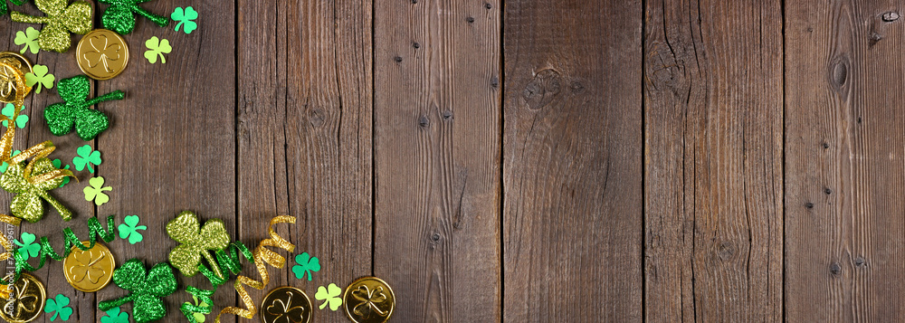 Poster st patricks day corner border of green shamrocks, gold coins and ribbon. top down view over a rustic
