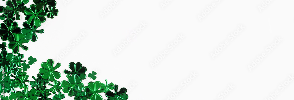 Poster St Patricks Day corner border of  shiny shamrocks. Top down view over a white banner background with copy space.