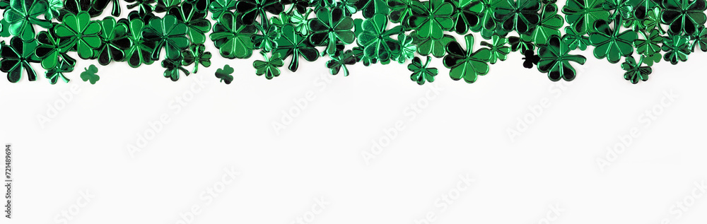 Poster St Patricks Day top border of  shiny shamrocks. Above view over a white banner background with copy space.