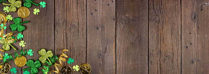 St Patricks Day corner border of green shamrocks, gold coins and ribbon. Top down view over a rustic dark wood banner background with copy space. - obrazy, fototapety, plakaty