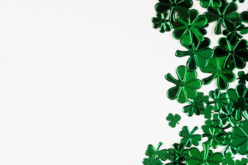 St Patricks Day side border of  shiny shamrocks. Overhead view over a white background with copy space.