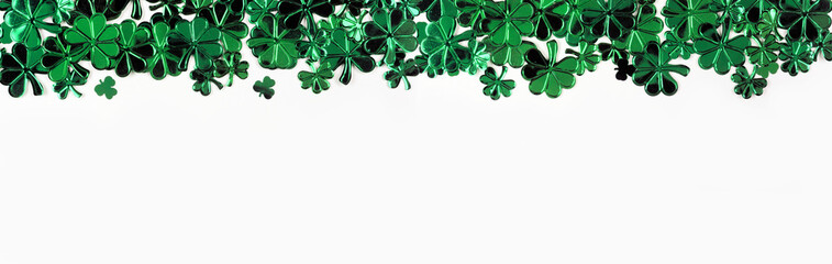St Patricks Day top border of  shiny shamrocks. Above view over a white banner background with copy...