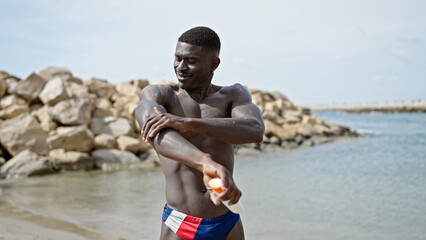 African american man tourist standing shirtless applying sunscreen at the beach