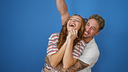 Naklejka premium Happy couple embracing and laughing together against a blue background, depicting love and joy in a relationship