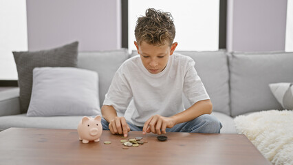 Adorable little blond boy, seriously engaged in counting coins, comfortably sitting on the cozy sofa. indoor relaxation and serious concentration, a valuable lesson in saving and investment at home. - obrazy, fototapety, plakaty