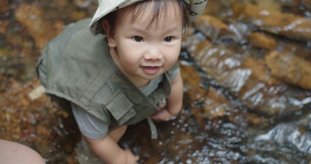 cute little Asian toddler daughter kid girl standing playing mountain river water creek nature in forest natural background, adventure camping travel trip