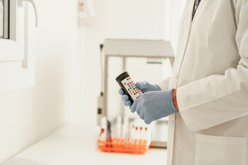 Close up of scientist's hand in gloves putting a small plastic test tube in a microcentrifuge