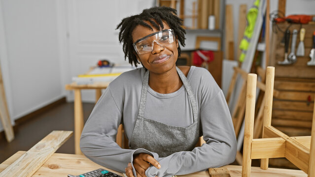 African american woman with dreadlocks wearing safety glasses in a carpentry workshop