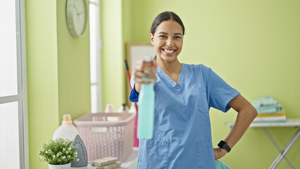 African american woman professional cleaner holding sprayer smiling at laundry room