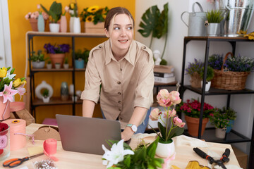 Young caucasian woman florist smiling confident using laptop at flower shop