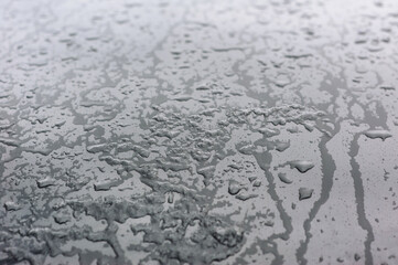 Background, texture of a black surface in flowing drops of water from melted snow and ice. Close-up photography, abstraction, top view, melting process.