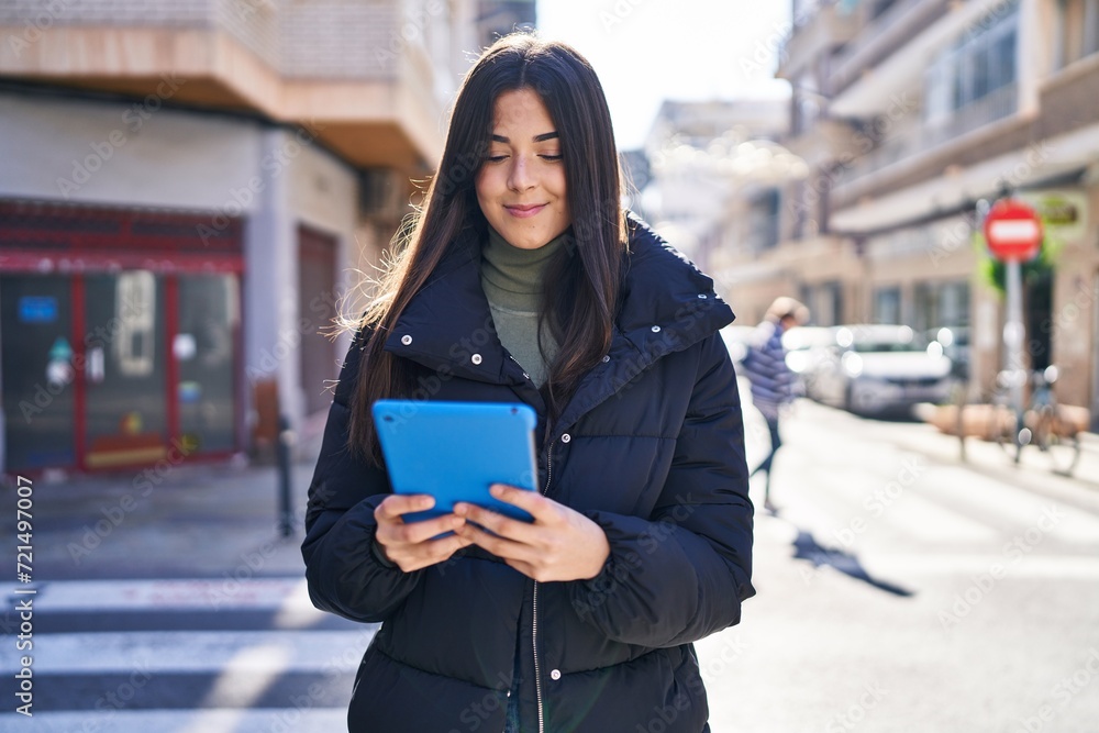 Poster Young beautiful hispanic woman smiling confident using touchpad at street