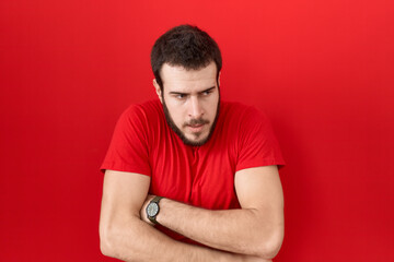 Obraz premium Young hispanic man wearing casual red t shirt shaking and freezing for winter cold with sad and shock expression on face