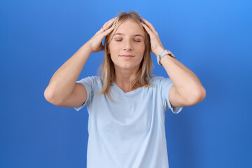 Young caucasian woman wearing casual blue t shirt suffering from headache desperate and stressed because pain and migraine. hands on head.
