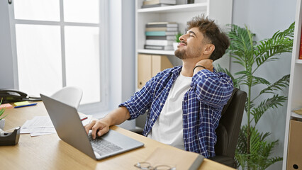 Overworked arab businessman suffering from cervical pain in office, tired young worker stressed...