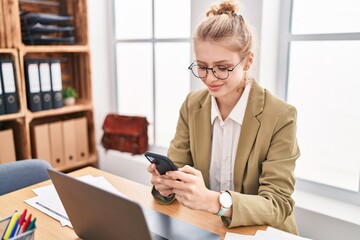 Young blonde woman business worker using laptop and smartphone at office