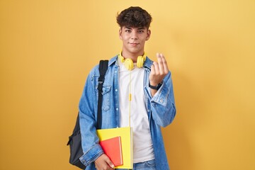 Hispanic teenager wearing student backpack and holding books doing italian gesture with hand and...