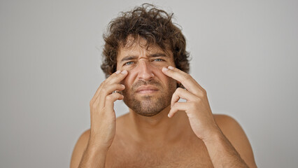 Young hispanic man touching dark circle and wrinkle over isolated white background