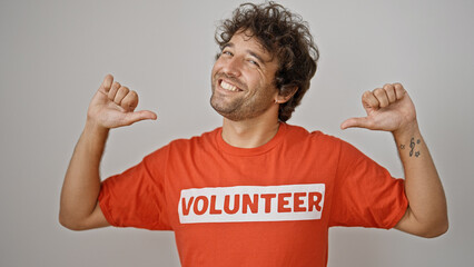 Young hispanic man activist pointing to volunteer uniform smiling over isolated white background