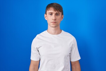 Caucasian blond man standing over blue background skeptic and nervous, frowning upset because of problem. negative person.