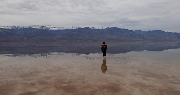 Death Valley Badwater Basin lowest in USA woman walk water. Largest national park in contiguous USA. 282 feet below sea level. Mojave Desert bordering Great Basin Desert. Ecological geology. 