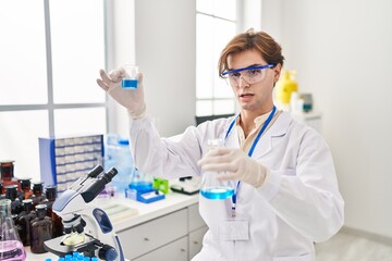 Young caucasian man scientist holding test tubes at laboratory