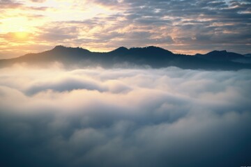 Obraz premium A beautiful sunset scene with the sun setting over the clouds and mountains. Perfect for nature and landscape themes