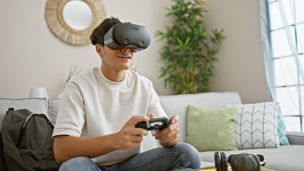 Happy young hispanic teenager joyfully playing trendy 3d video game, engrossed in using high-tech...