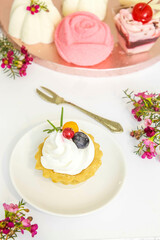 A cupcake with cream on a plate, a mini dessert plate in the background.