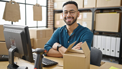 Young hispanic man ecommerce business looking happy at the camera at office