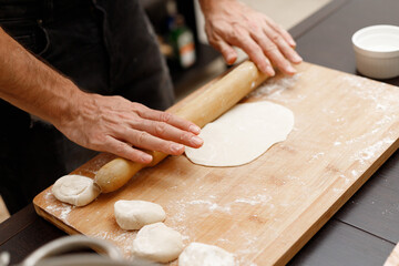 A young guy cooks from dough at home. Manti dumplings
