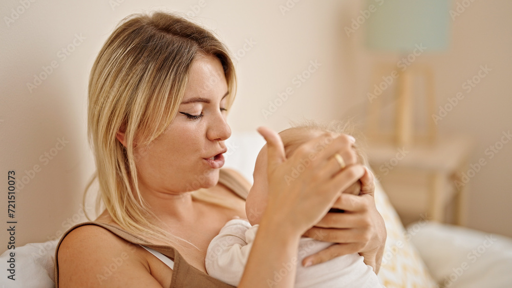 Sticker mother and daughter lying on bed hugging at bedroom