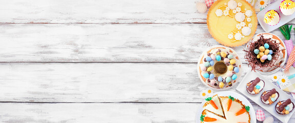 Easter or spring dessert food side border. Top view over a white wood banner background. Lemon tart, cupcakes, Easter egg and carrot cakes and an assortment of sweets. Copy space. - 721510664