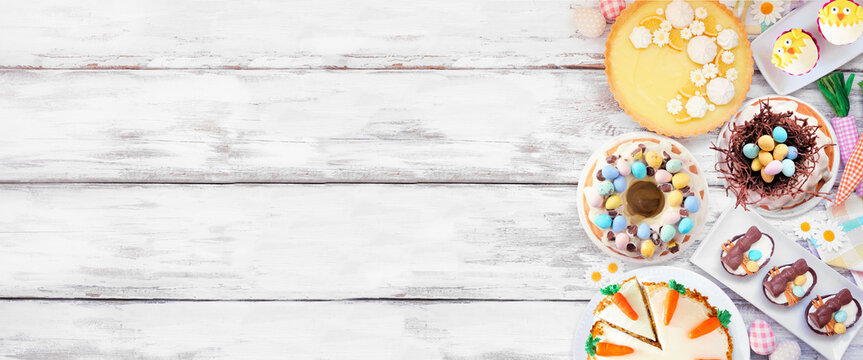 Easter or spring dessert food side border. Top view over a white wood banner background. Lemon tart, cupcakes, Easter egg and carrot cakes and an assortment of sweets. Copy space.