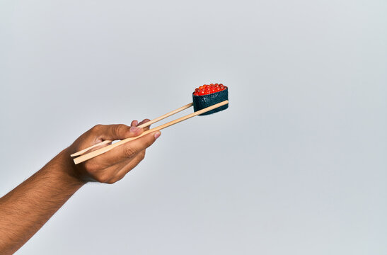  Hand of man holding salmon roe sushi with chopsticks over isolated white background