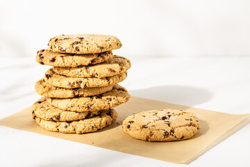 Chocolate chip cookies stacked on white plaster surface

