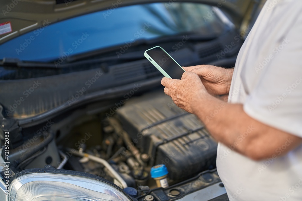 Canvas Prints Middle age grey-haired man using smartphone checking car motor at street