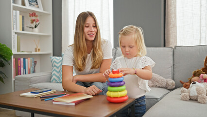 Happy caucasian mother and daughter enjoy a relaxed hoop game, sitting comfortably on the living room sofa at home.