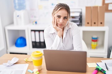 Young blonde woman business worker sitting on table with relaxed expression at office
