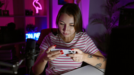 Young brunette woman intently gaming on smartphone in dimly lit room with neon lights.