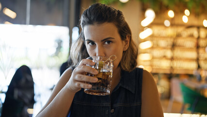 Young beautiful hispanic woman drinking a glass of vermouth at the restaurant